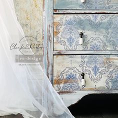 an old dresser has been painted with blue and white floral wallpaper, along with a sheer curtain