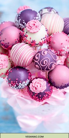 a vase filled with lots of pink and purple decorated chocolates on top of a table