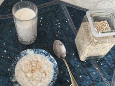 a bowl of oatmeal next to a glass of milk on a table