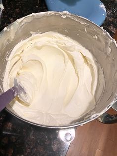 a metal bowl filled with white frosting on top of a counter