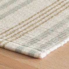 a close up of a rug on a wooden floor with white and blue stripes in the middle