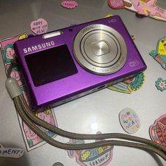 a purple camera sitting on top of a table covered in stickers and magnets