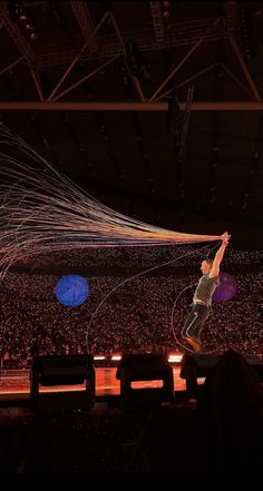 a man is performing on a stage in front of an audience with strings flying through the air