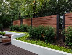 a wooden deck with benches and plants in the foreground, next to a fence