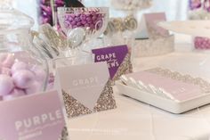 candy bar with purple and silver candies on white table clothed tablecloths