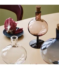 three wine glasses sitting on top of a table next to a bottle and glass vase