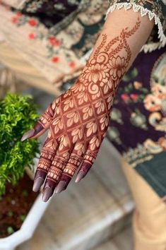 a woman's hand with hennap on it and flowers in the background