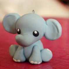 a small blue elephant figurine sitting on top of a red table next to a cup