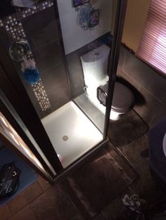 a small bathroom with a shower and toilet in it's stall, looking down at the floor