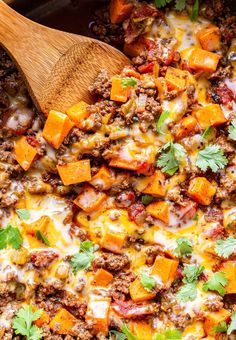 a casserole dish with meat, cheese and vegetables in it next to a wooden spoon