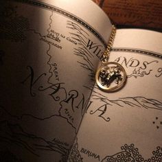 a close up of a book with a necklace on it's cover and a map in the background