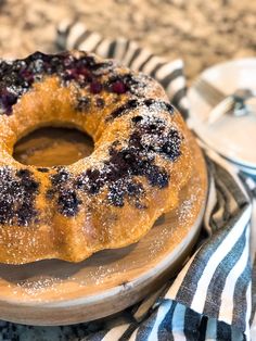 a blueberry bunt cake on a plate with a striped napkin and spoons