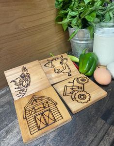 four wooden coasters with farm animals on them next to some vegetables and an egg