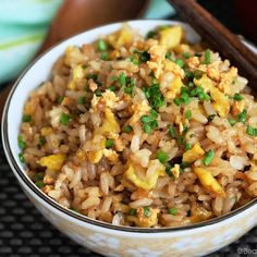 a bowl filled with rice and vegetables next to chopsticks