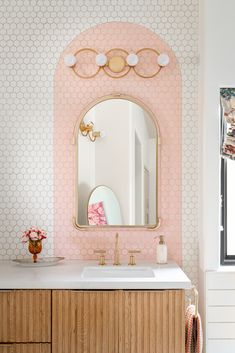 a bathroom with pink and white wallpaper, gold mirror and vanity in the corner