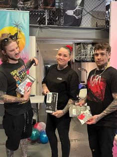 three people standing next to each other with tattoos on their arms and holding boxes in front of them