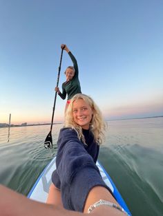 two people in a boat on the water, one holding onto another person's hand