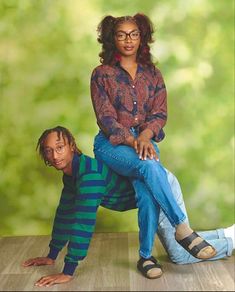 a woman sitting on top of a man's lap in front of a green background