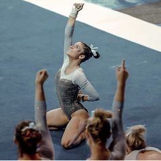 a woman is sitting on the floor with her arms in the air