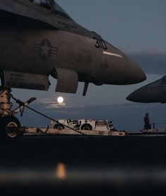 an airplane sitting on top of an airport tarmac next to another plane with the moon in the background