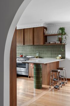 a kitchen with wooden floors and green tile backsplash