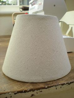 a white lamp shade sitting on top of a wooden table next to a laptop computer