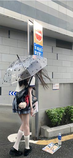 a woman walking down the street with an umbrella and teddy bear in her hand,