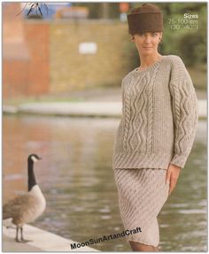 a woman standing next to a goose wearing a sweater and skirt