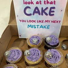 cupcakes with purple frosting are in a box next to a sign that says, look at that cake you look like my next mistake