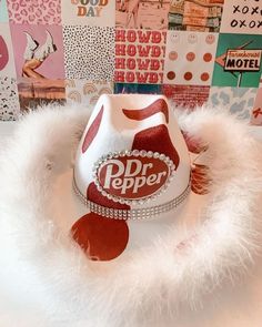 a red and white hat sitting on top of a pile of paper with pictures behind it