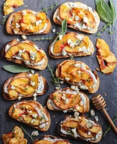 toasted bread topped with peaches and cream cheese on a slate board next to a honey comb