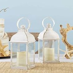 two white lanterns sitting on top of a table