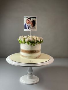 a wedding cake with a photo on top and flowers in the bottom, sitting on a pedestal