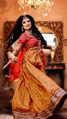 a woman in a yellow and red dress dancing with a chandelier above her head