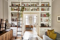 a living room filled with furniture and bookshelves next to a doorway that leads to a bedroom