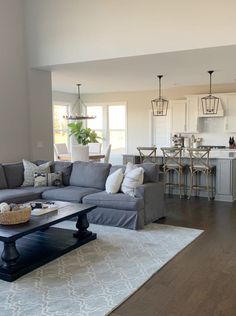 a living room filled with furniture next to a kitchen and dining room table on top of a hard wood floor