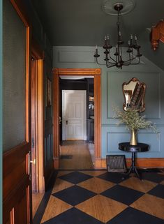 a hallway with a checkered floor and chandelier hanging from it's ceiling