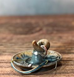 a small metal bowl with a snail on it's top and rope around the base