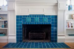 a fireplace with blue tiles in the middle and shelves on either side that have bookshelves