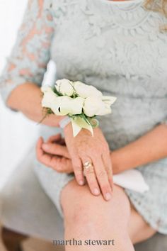 a woman sitting on a chair holding a bouquet of white flowers in her hand,