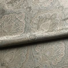 a close up view of the fabric on a bed sheet with an intricate paisley pattern