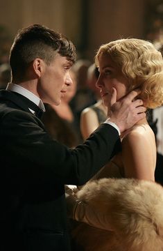 a man in a tuxedo is hugging a woman's face at an event