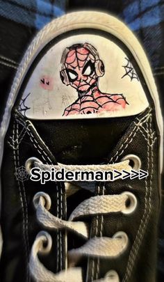 a pair of black and white shoes with spiderman painted on them