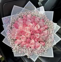 a bouquet of pink roses and baby's breath in the back seat of a car