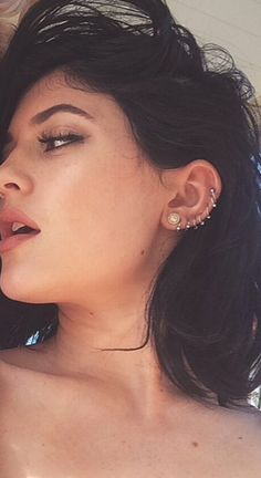 a close up of a person talking on a cell phone and wearing ear studs