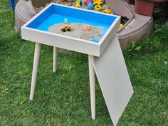 a table with sand and toys in it on the grass