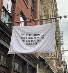 a sign hanging from the side of a building that says pay attention to who you're with when you feel your best