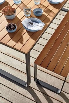 a wooden table with two bowls of food on it next to a bowl of fruit