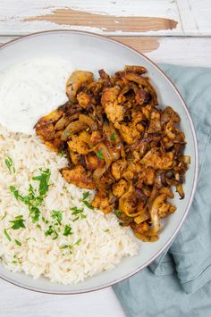 a white plate topped with rice and meat