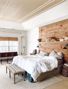 a bedroom with a large bed and wooden headboard on the wall next to a window